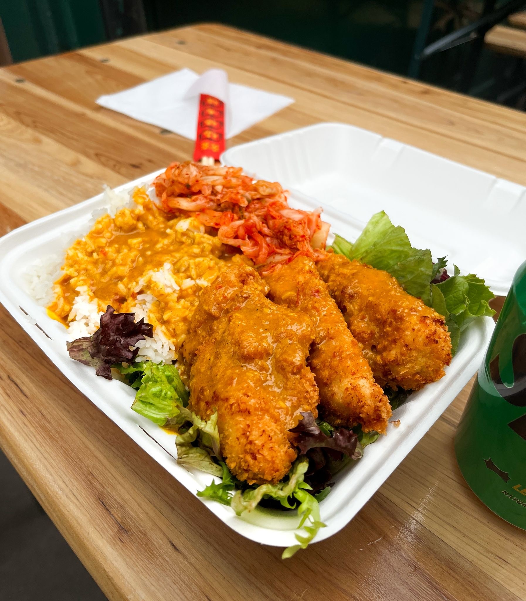 A container from XO, filled with fried chicken and Katsu sauce, rice and salad