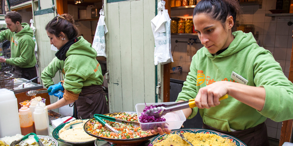 A lady in a green jumper putting red cabbage into a plastic container