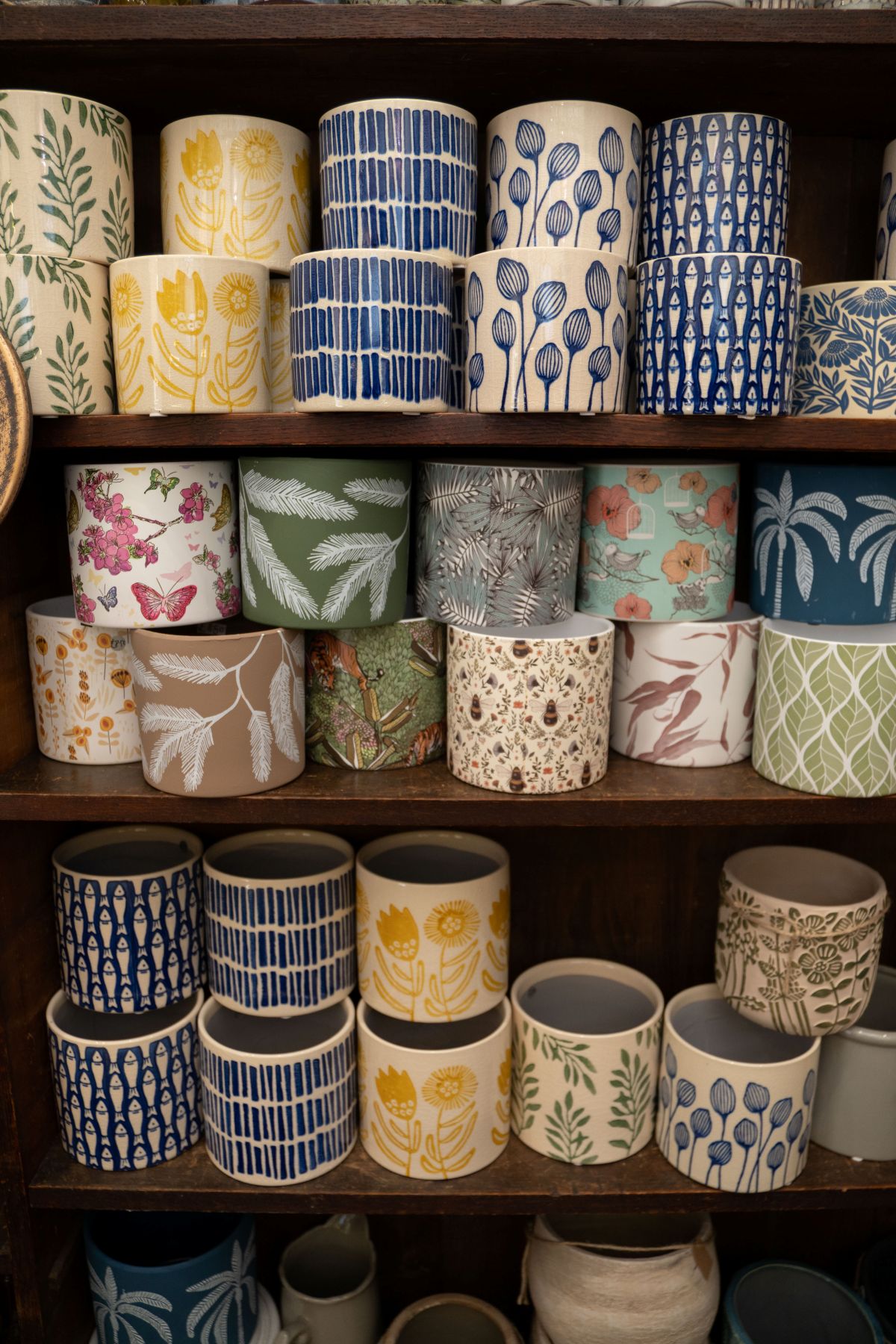 Some colourful and patterned cups on a shelf