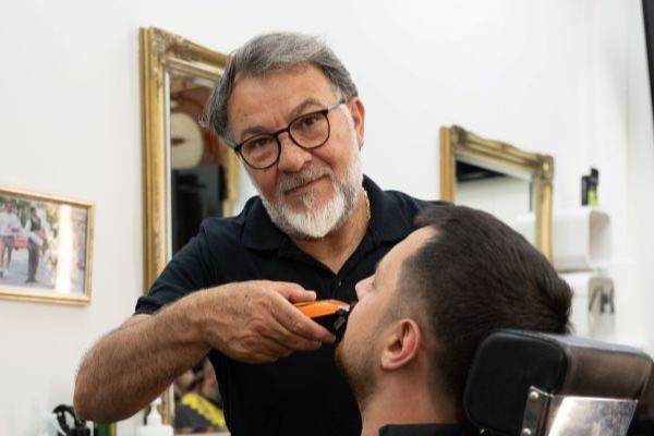 A man cutting the hair of another man in a chair