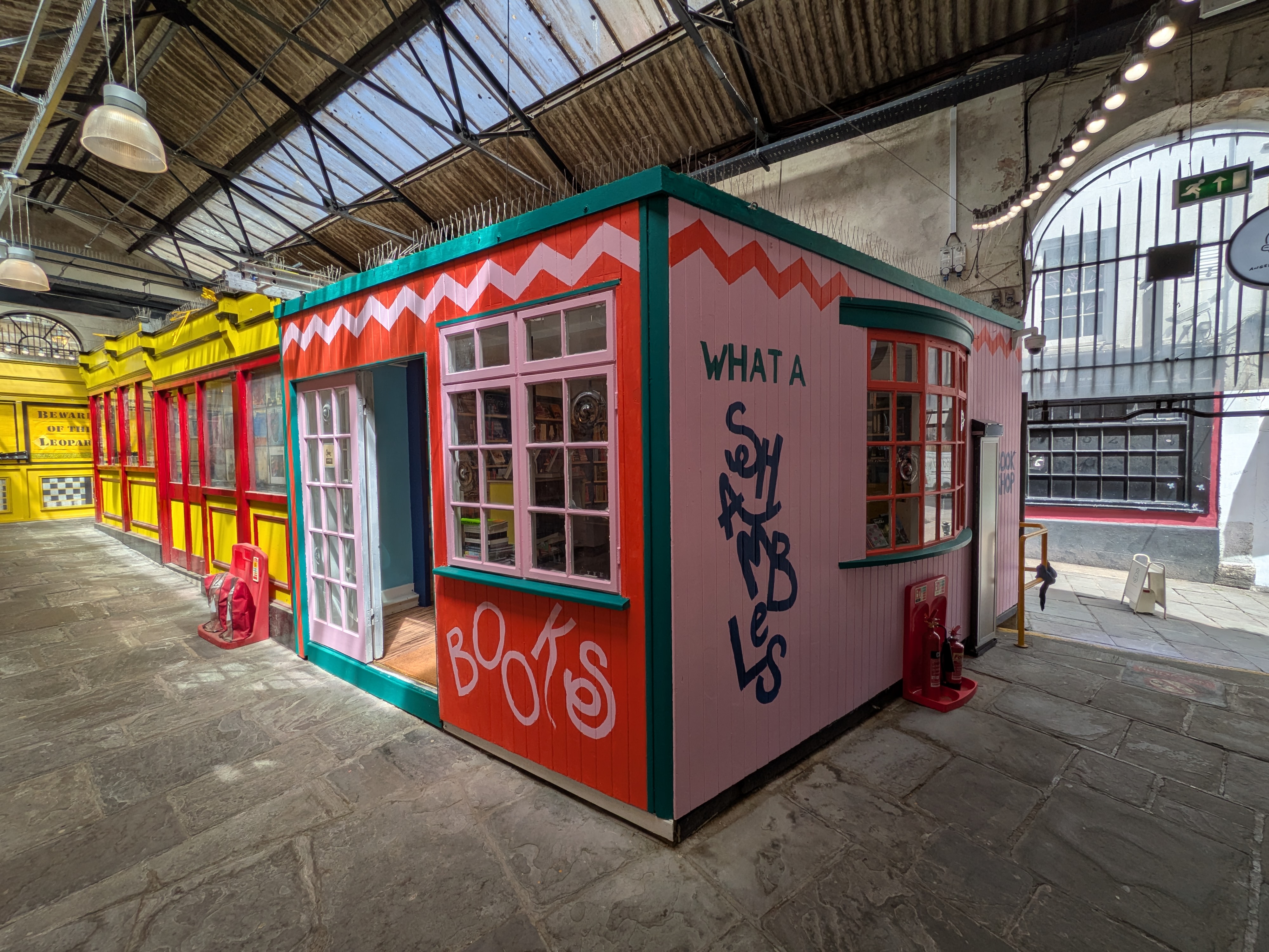 The exterior of Shambles Bookshop. Colourful red and pink walls with green decorations
