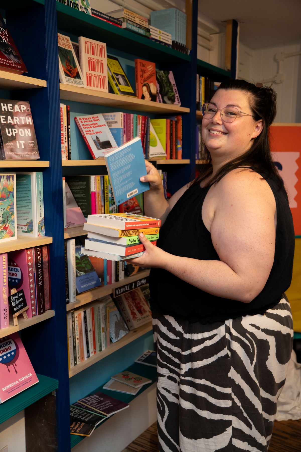 A smiling employeee putting books on a bookshelf