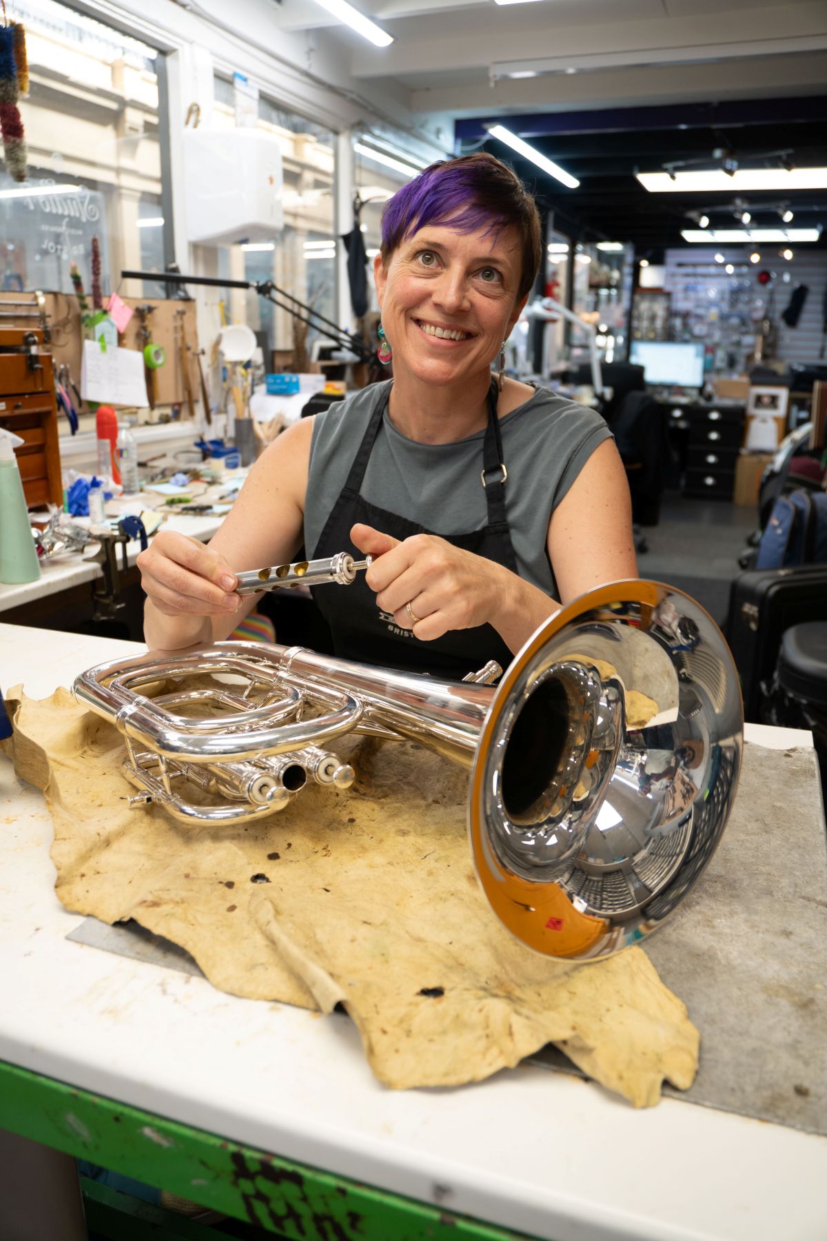 A woman smiling and repairing an instrument