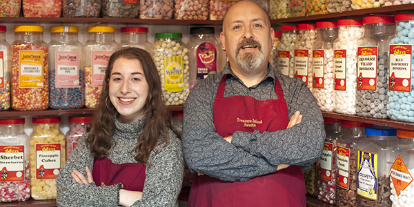 a man and a lady stood in front of lots of jars of yummy swerets