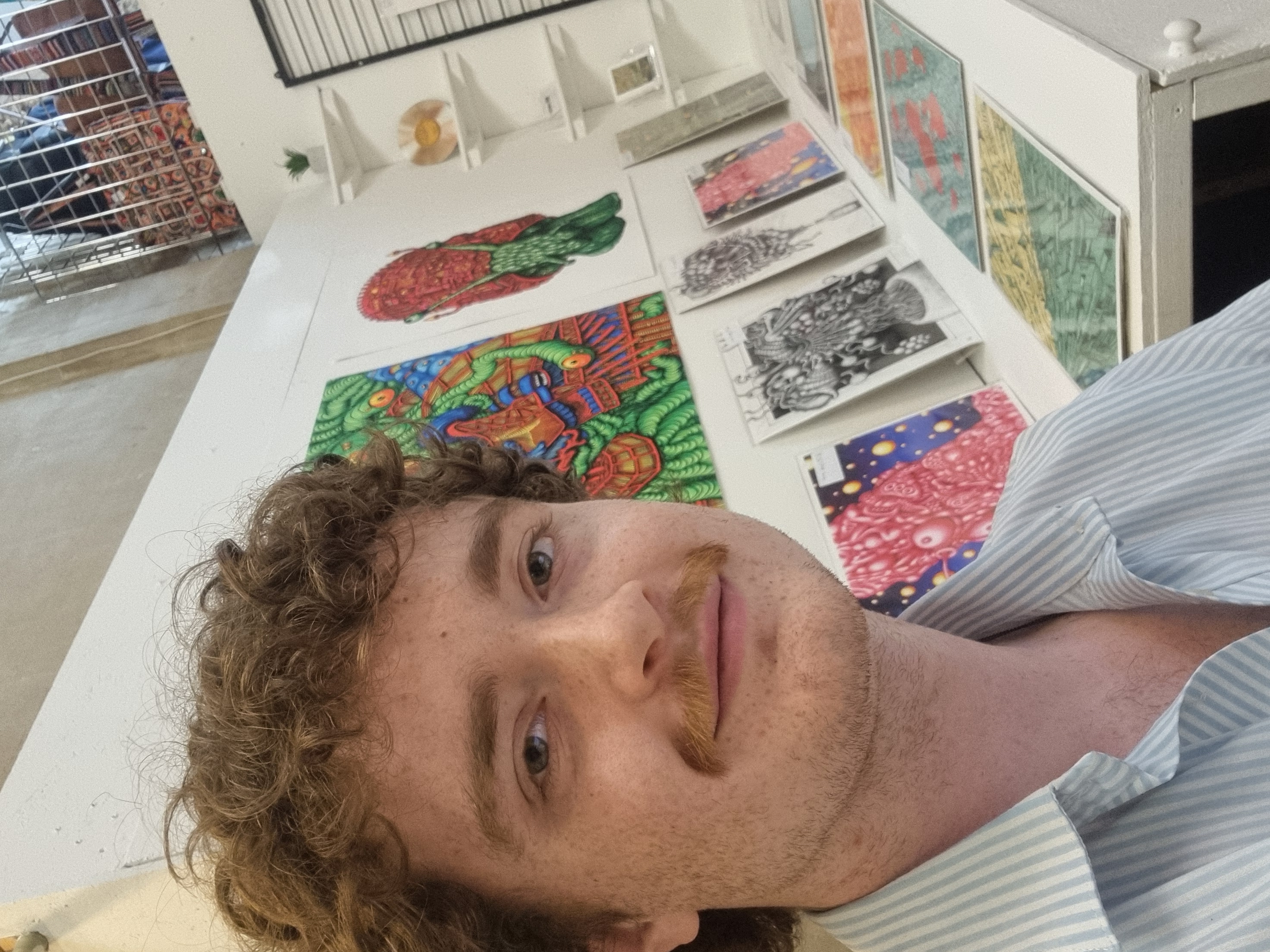 A man posing in front of some colourful print artwork