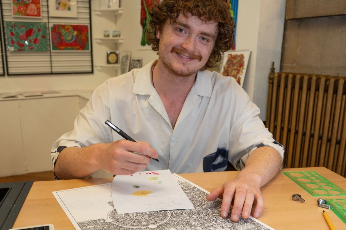 A man sitting at a table doing some art