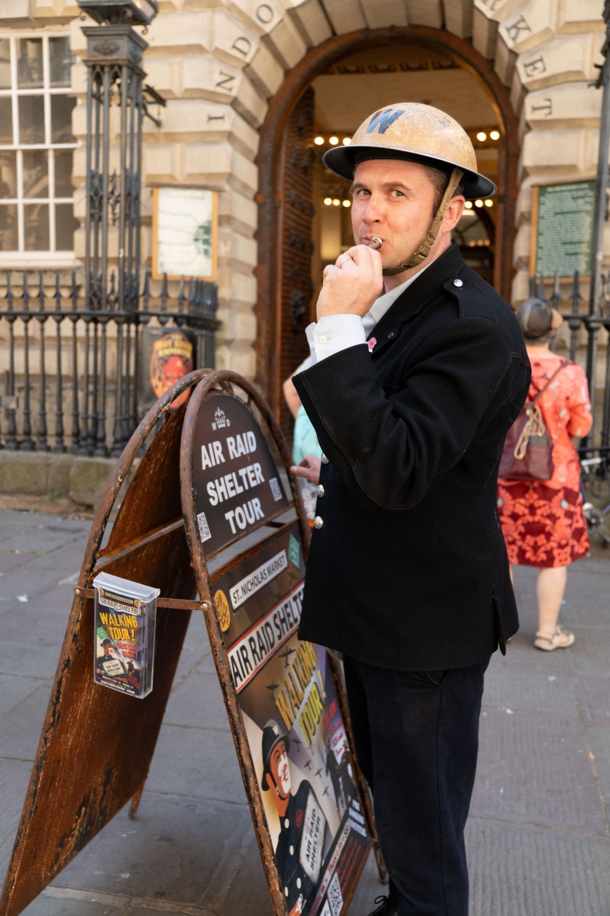 A man dressed as a Second world war warden stands in front of the exchange building blowing on a whistle