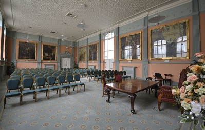 A large room with large paintings on the wall and many rows of chairs